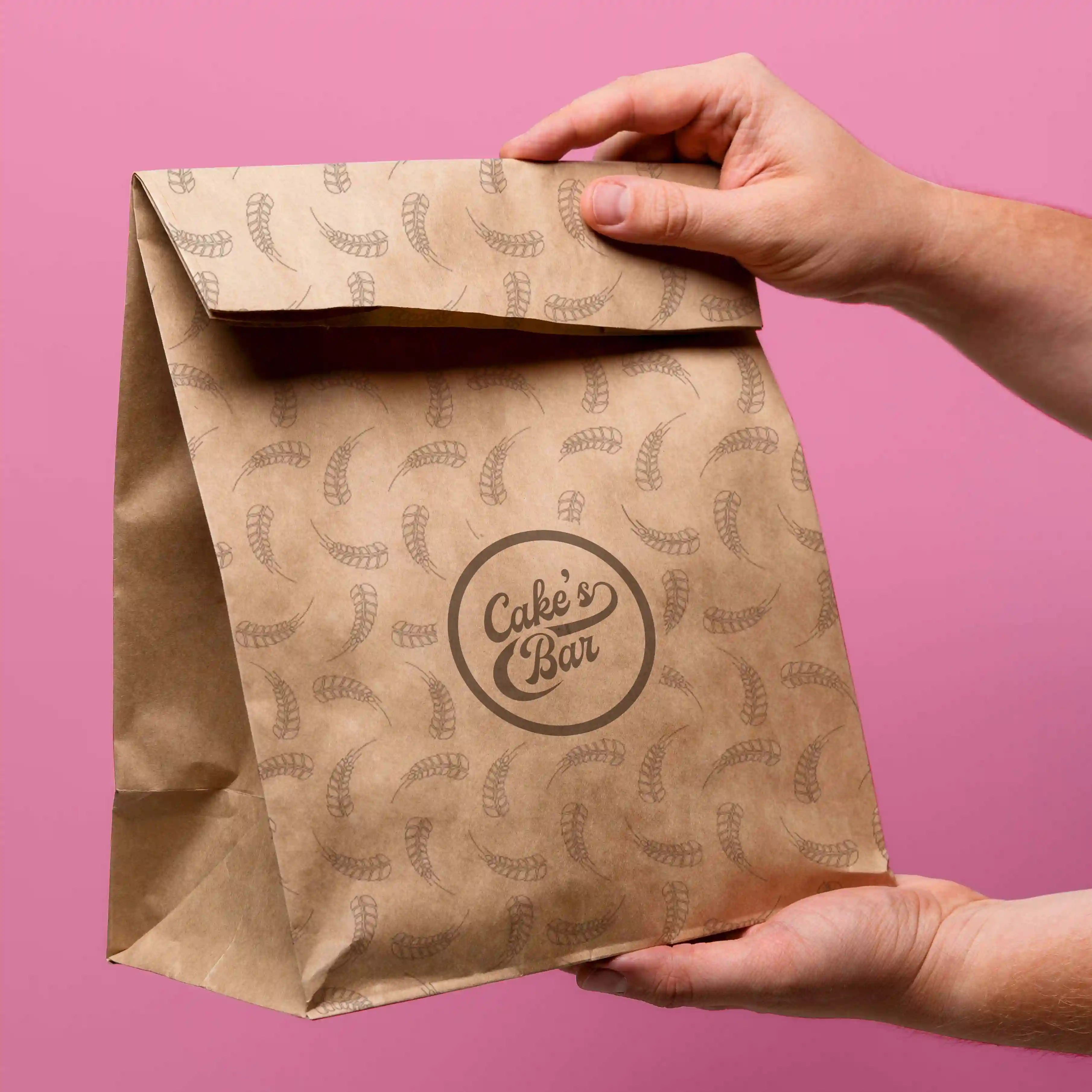 Dos manos sosteniendo una bolsa de papel impresa con el patrón de la marca.